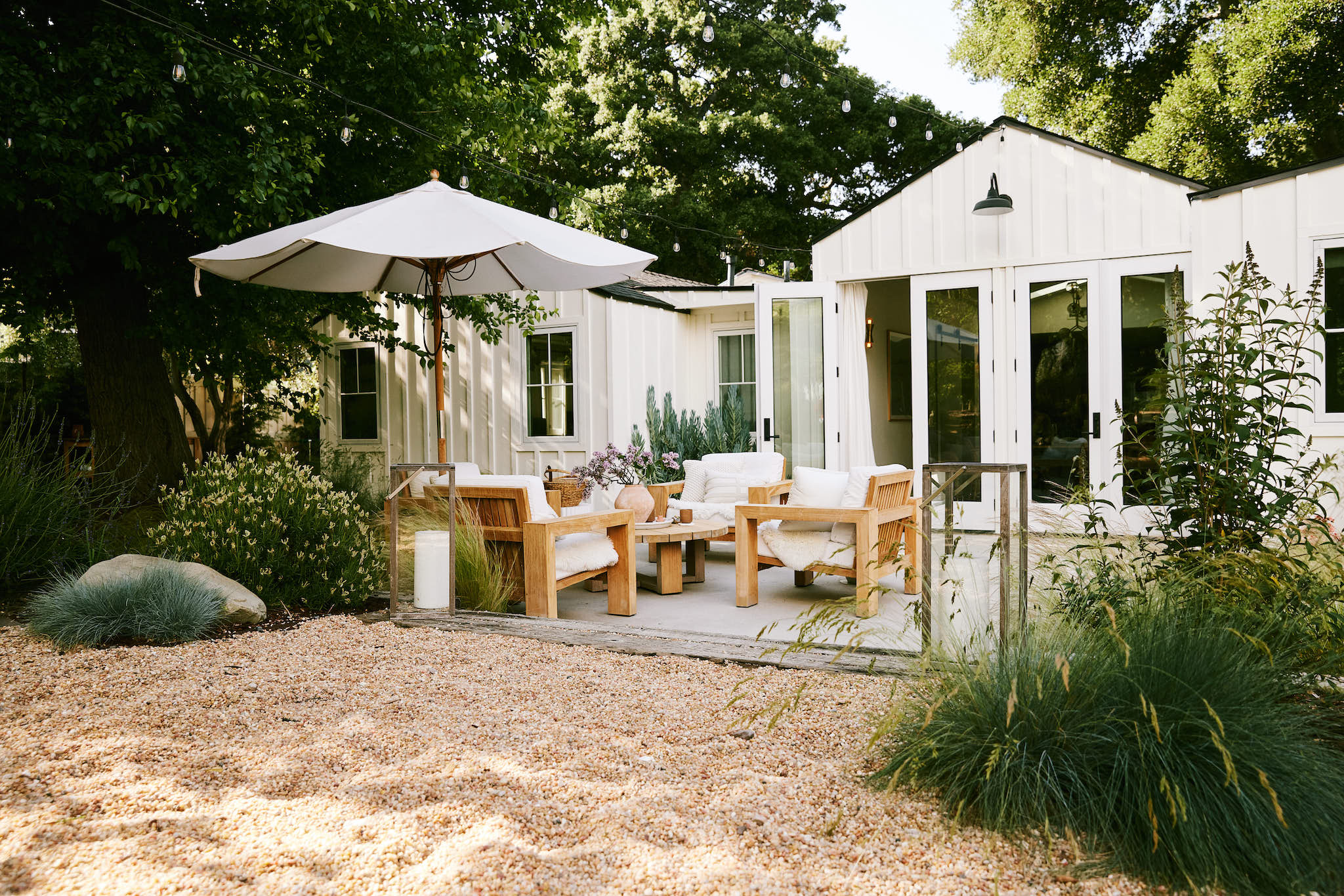 Backyard with pea gravel, shrubs, grasses and an outdoor gathering area with umbrella
