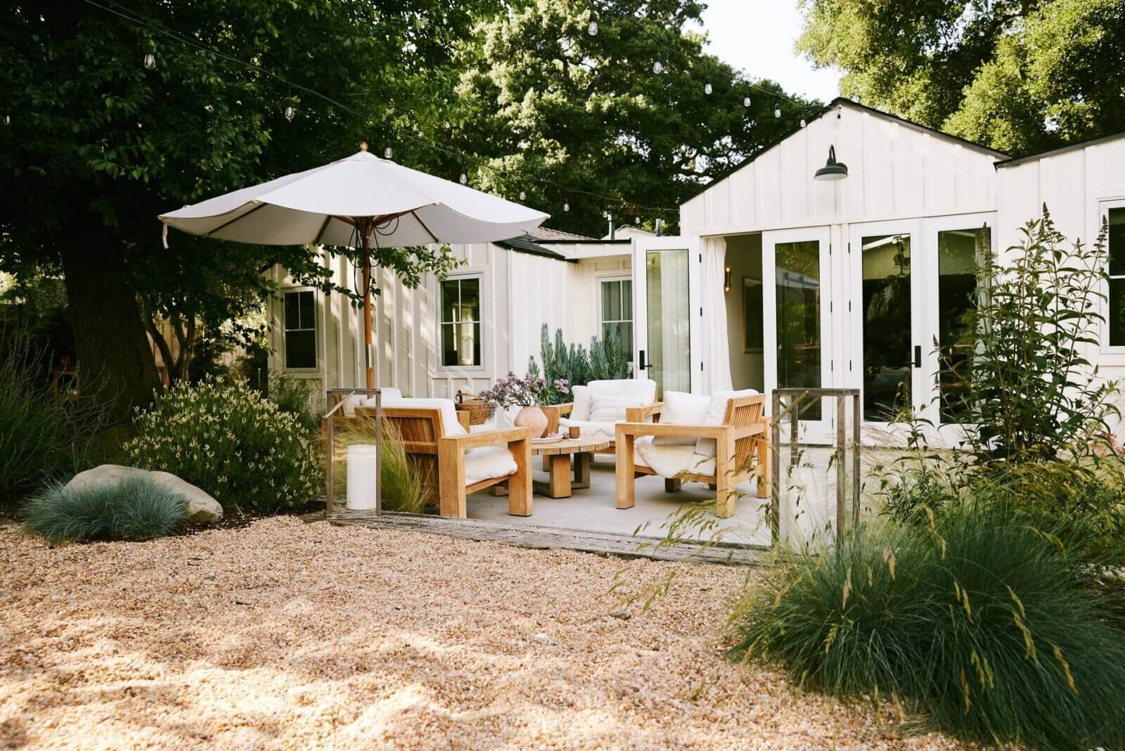 Modern farmhouse backyard with gravel near outdoor lounge area with umbrella