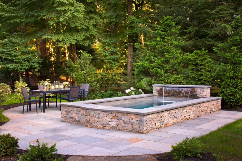 Rustic style plunge pool with waterfall near outdoor dining table area