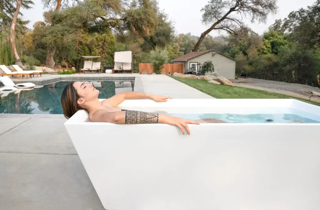 Woman laying in Plunge tub on backyard pool patio