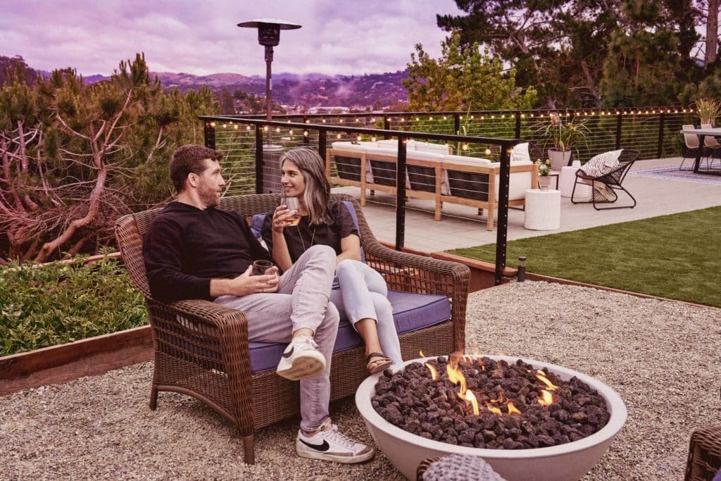 Couple sitting on loveseat near fire pit