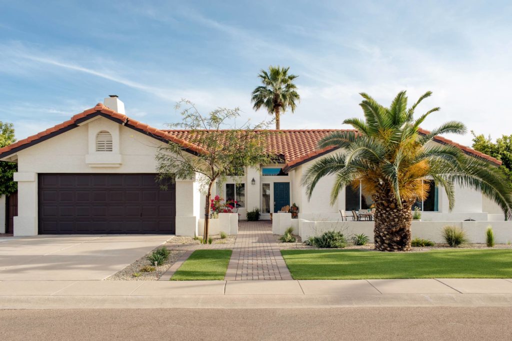 Front view of desert style home with artificial grass and paver walkway