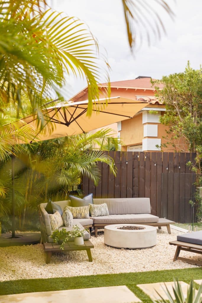 Tropical landscaping surrounding a new outdoor couch and fire pit area