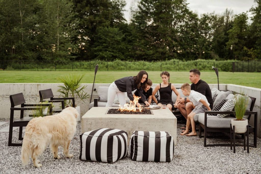 Family and white dog around an outdoor fire pit