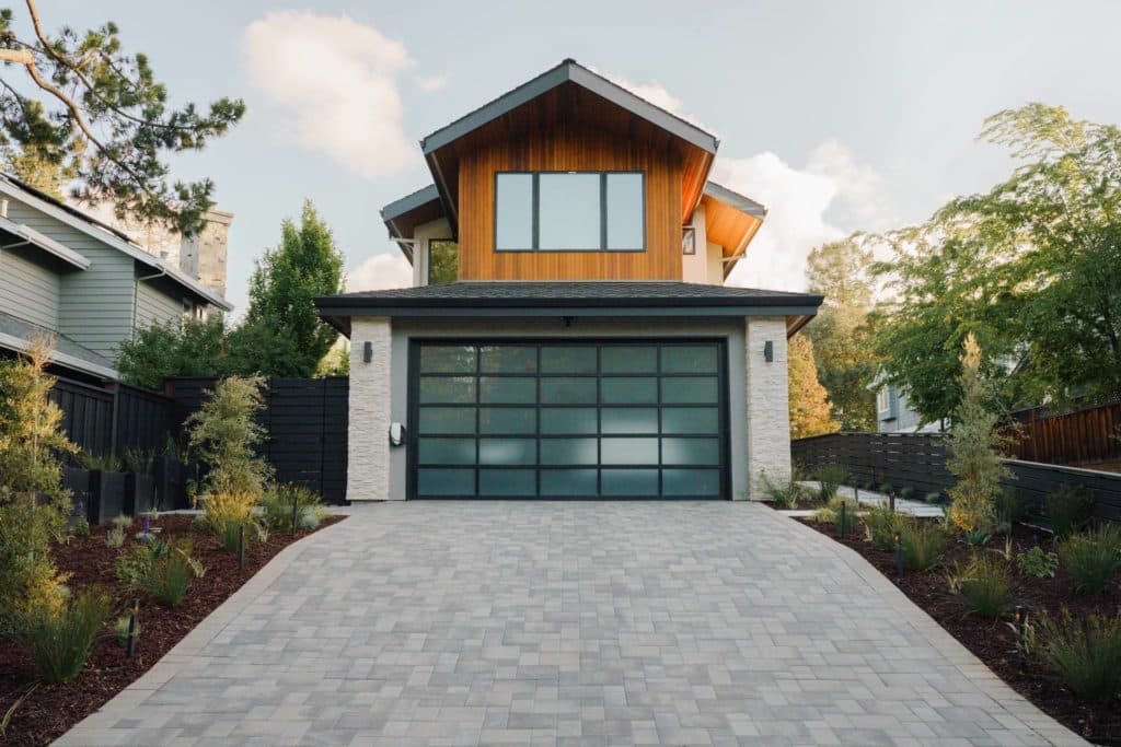 Modern two-story home with glass-paned garage door and paver driveway