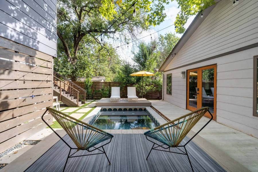 Small backyard with tiled concrete plunge pool with wooden decks with seating on either side.