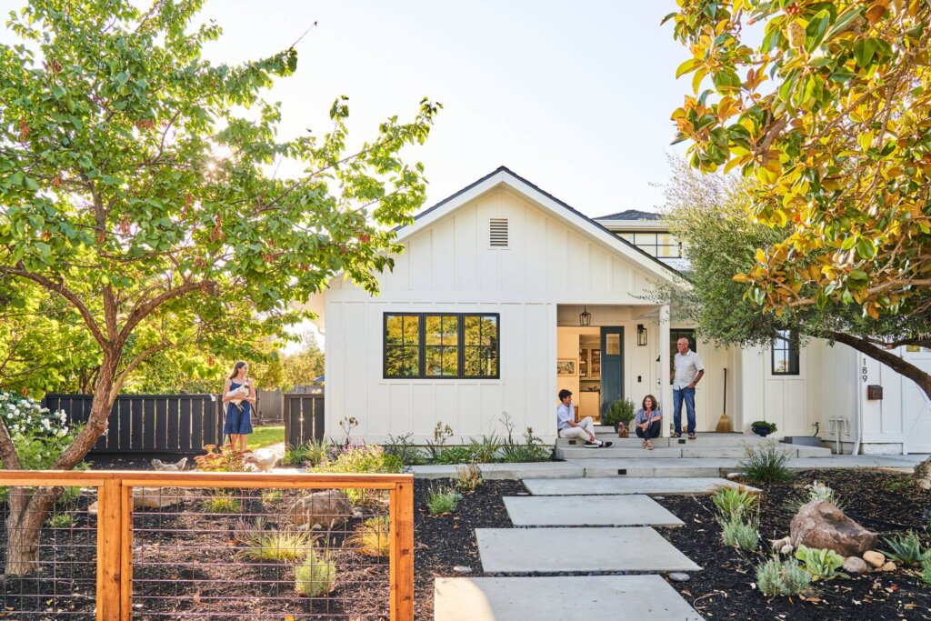 Family sitting in front yard of modern farmhouse